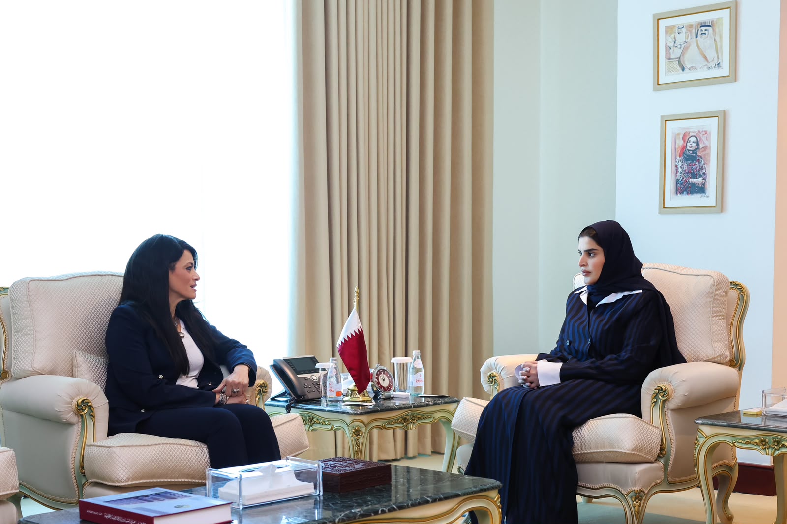 Two female officials seated on white couches