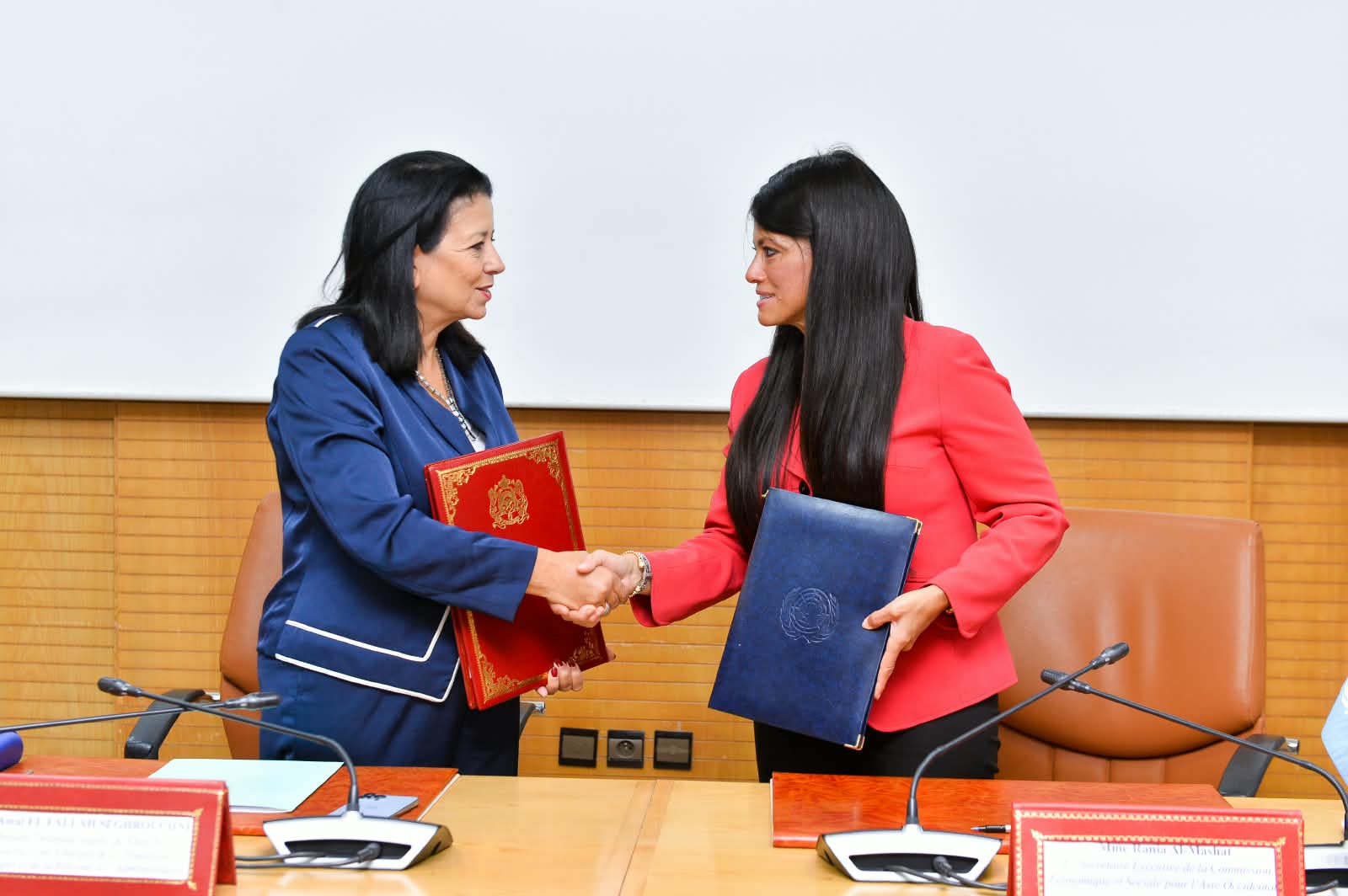 Two women senior officers shaking hands and holding a folder they just signed
