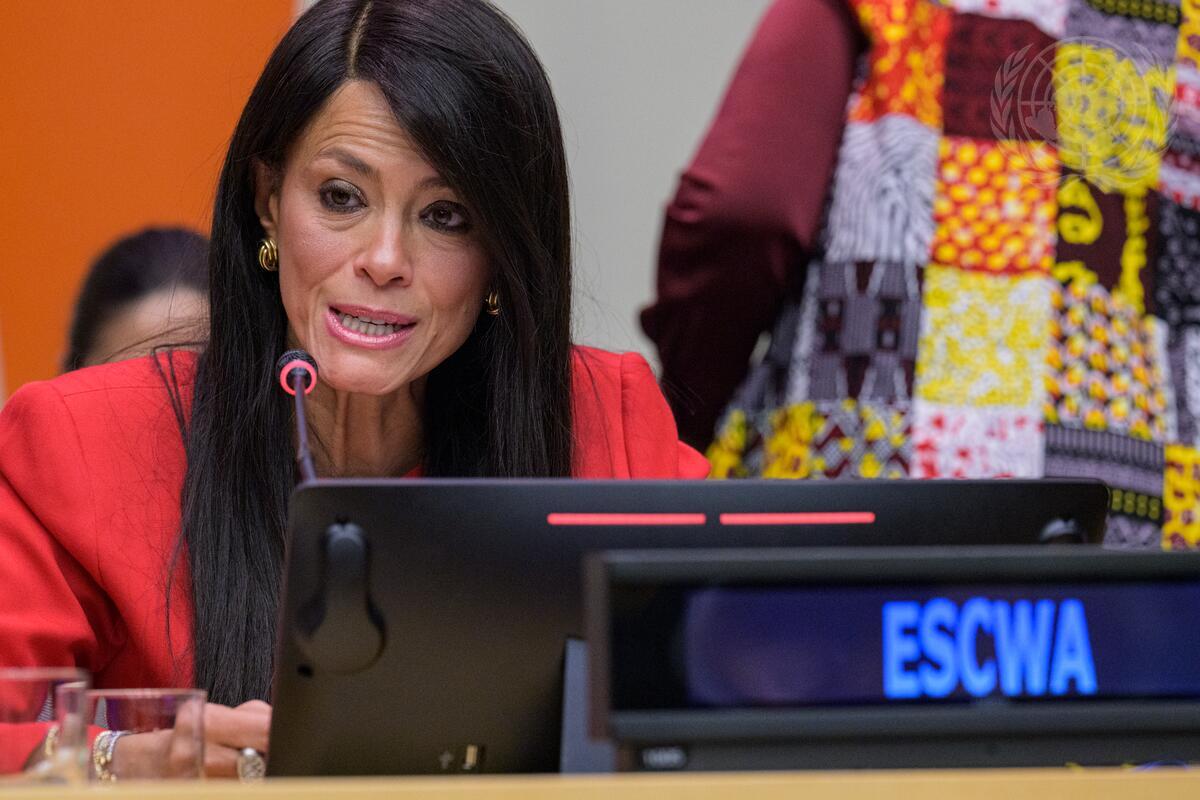 Woman speaking behind mic and ESCWA tag