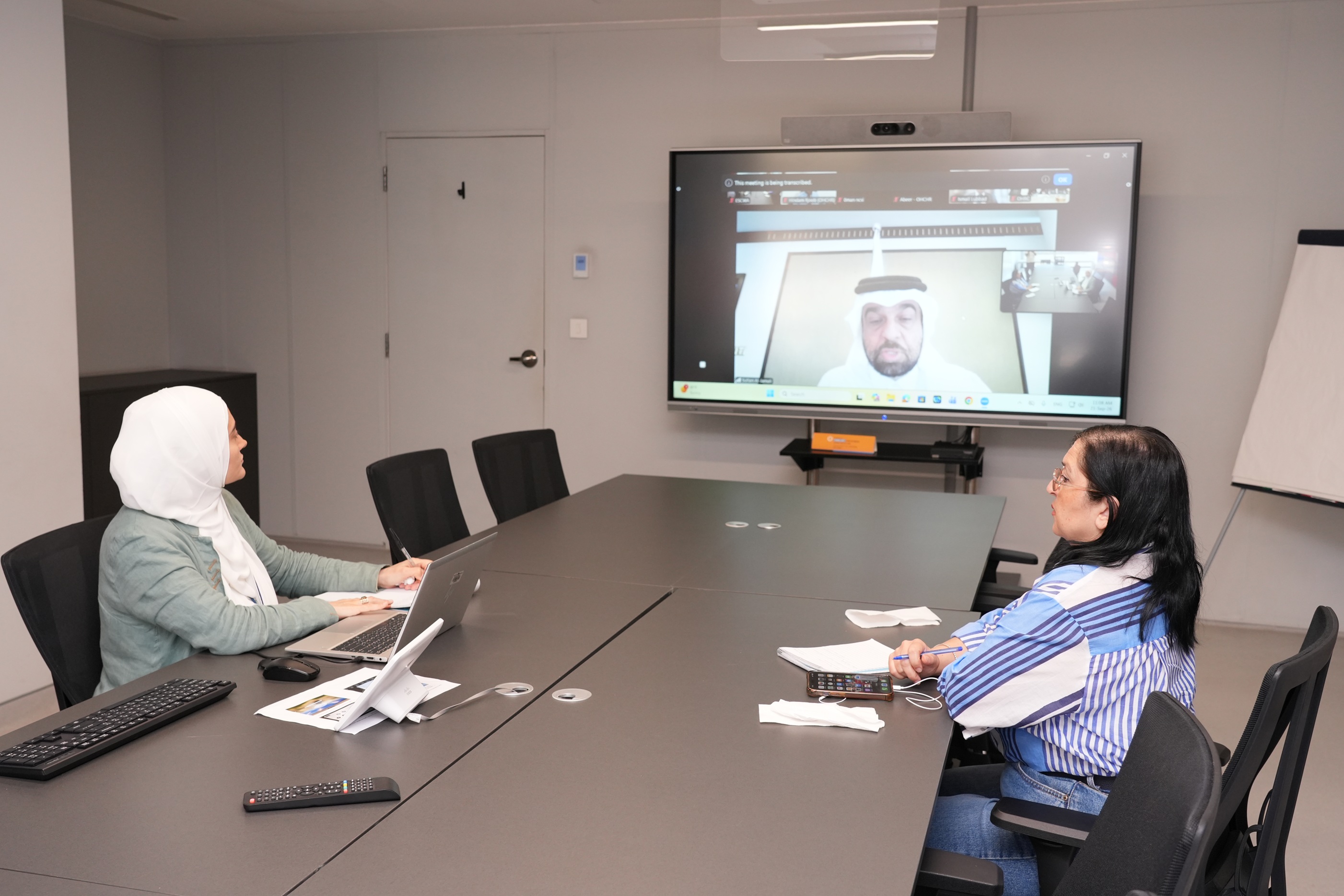 Two women seated around a table in a videoconference