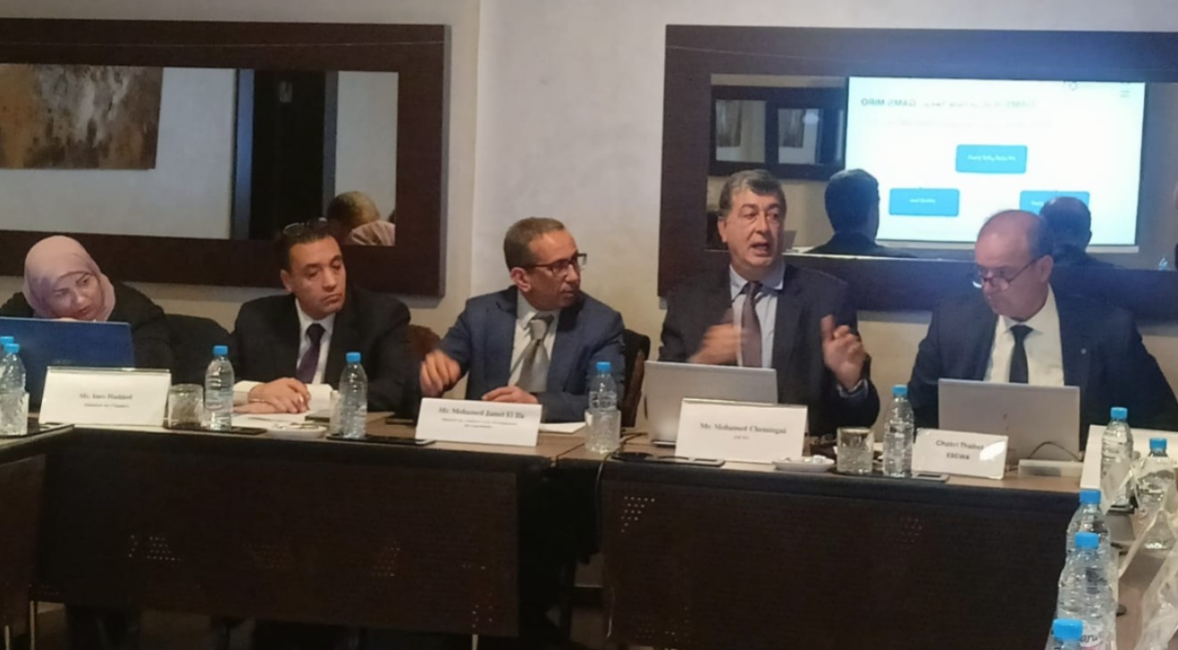 Presenter speaking in a panel behind a table