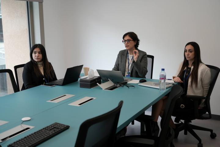 Speaker from ESCWA behind her laptop, surrounded by two women listening